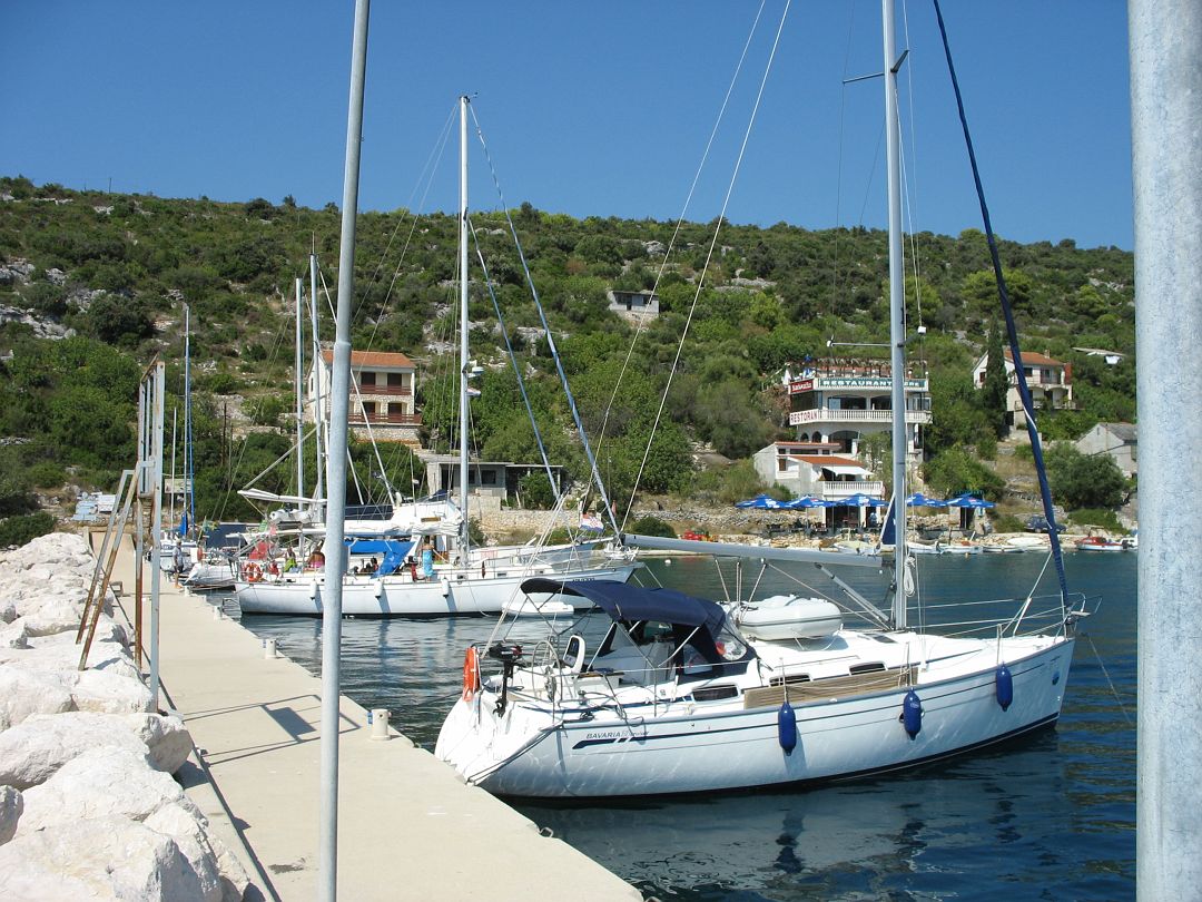 IMG_8306.JPG - Drvenyik. A nagy Drvenik. Itt nem volt mooring, horgony volt elöl. Danci ugrott ki kikötni a hajó hátulját. Víz nincs, bolt délután nyit. Akkor megyünk tovább. Talán a kis Dveniken lesz... De nem volt. Maximum víz helyett sört iszunk.